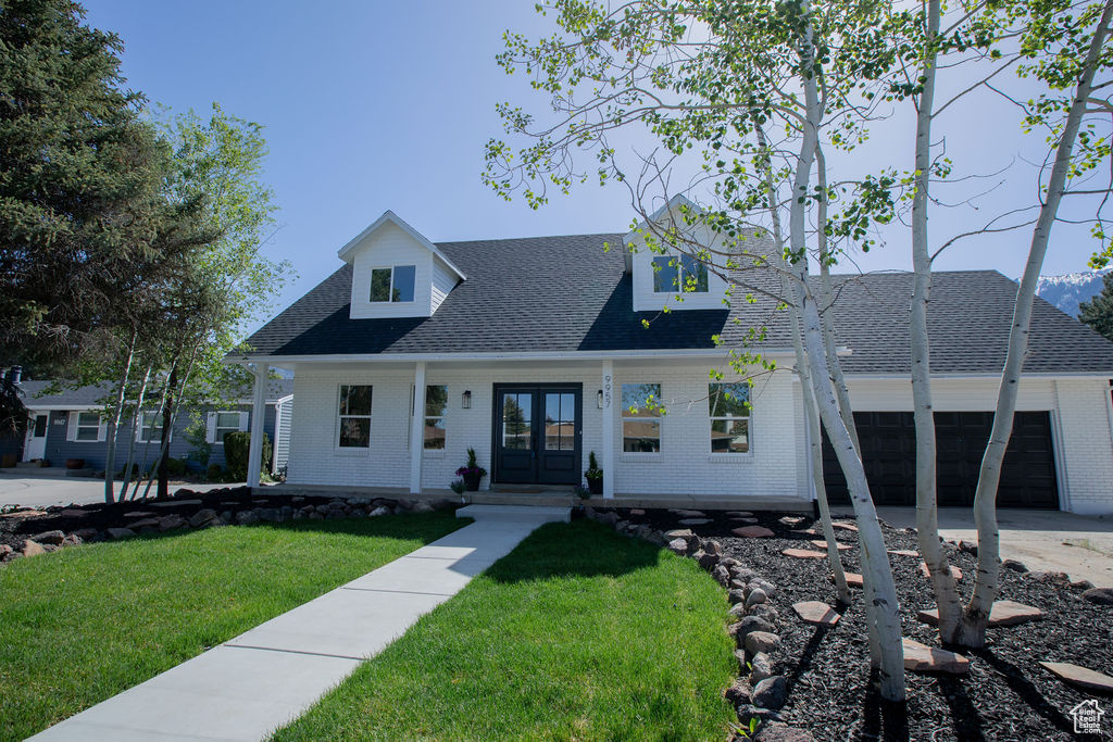 View of front facade featuring french doors, brick siding, and roof with shingles