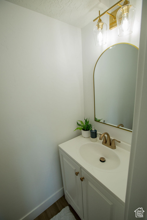 Bathroom with wood finished floors, vanity, a textured ceiling, and baseboards