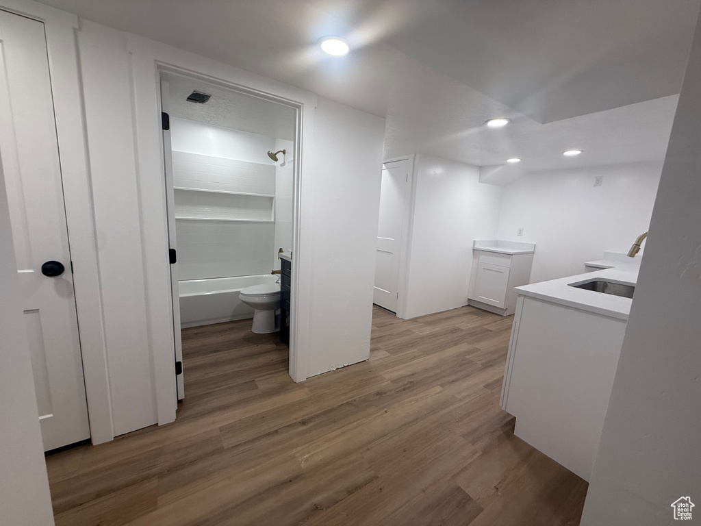 Laundry room featuring a sink, light wood finished floors, and recessed lighting