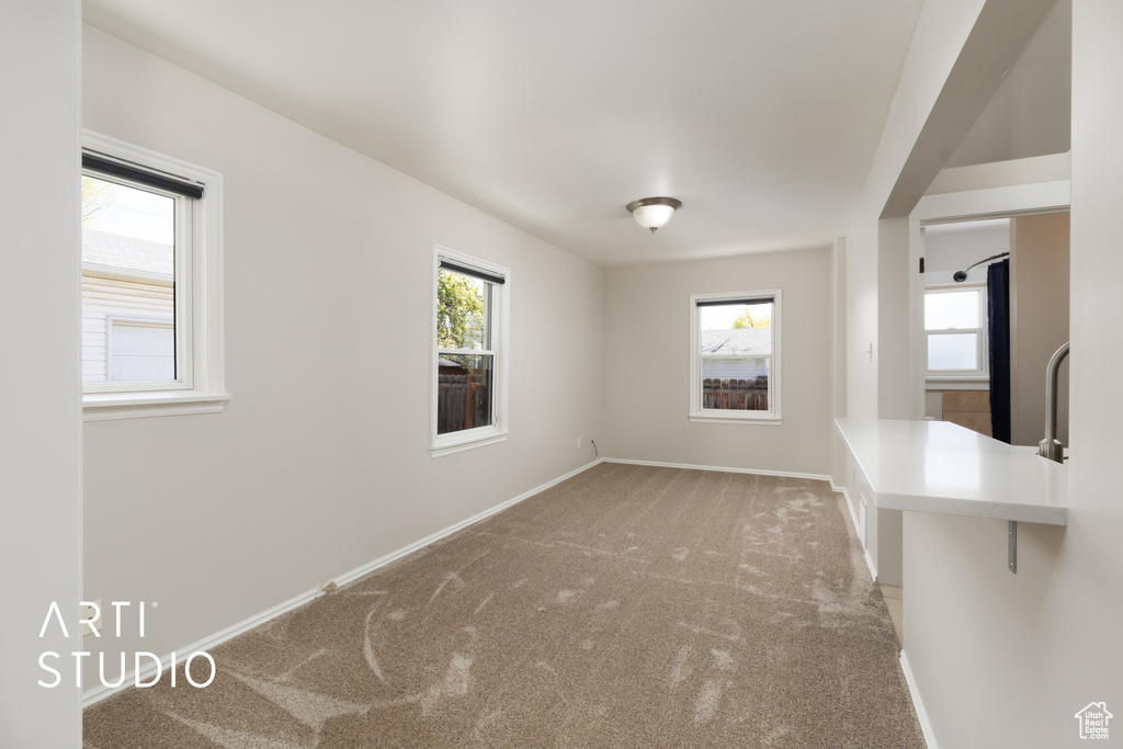 Unfurnished dining area featuring baseboards, a wealth of natural light, a sink, and carpet
