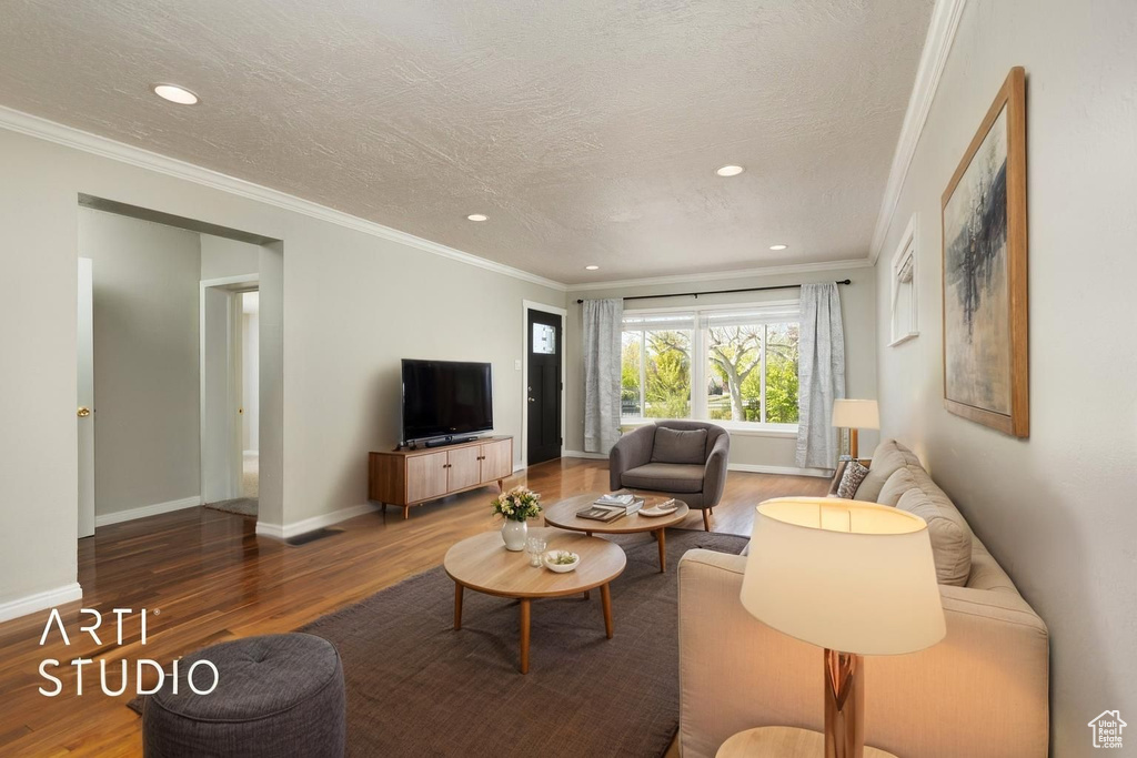 Living room with crown molding, wood finished floors, and recessed lighting