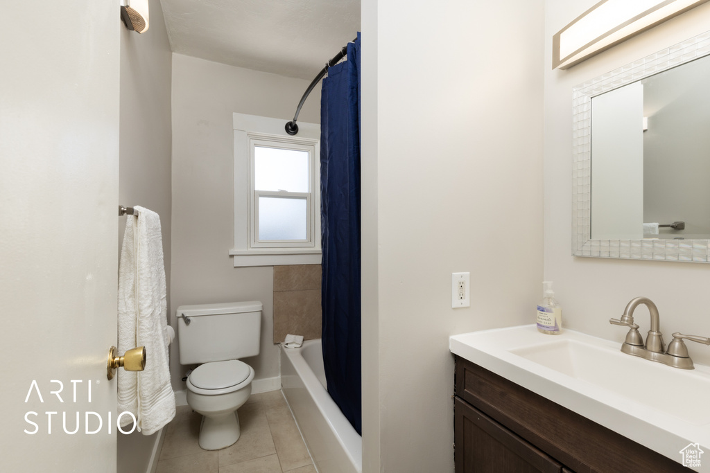 Bathroom featuring toilet, shower / bath combo with shower curtain, baseboards, tile patterned flooring, and vanity