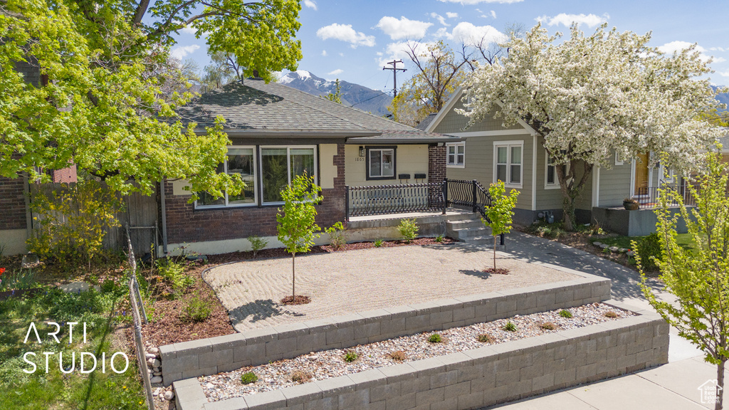 View of front of home with brick siding, a shingled roof, and a mountain view
