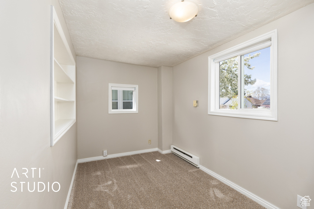 Unfurnished room with a baseboard heating unit, carpet, a textured ceiling, and baseboards