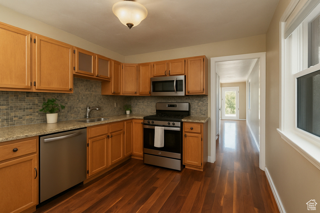 Kitchen featuring a sink, backsplash, dark wood-style floors, and appliances with stainless steel finishes