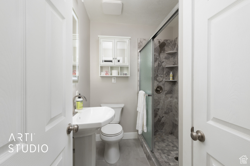 Full bathroom with a stall shower, baseboards, tile patterned floors, and toilet