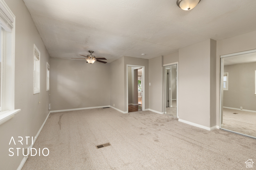 Carpeted spare room with visible vents, baseboards, and ceiling fan
