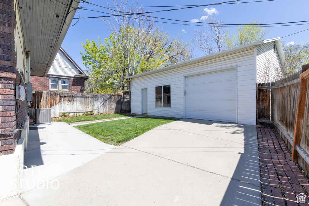 Detached garage featuring central air condition unit, fence, and concrete driveway
