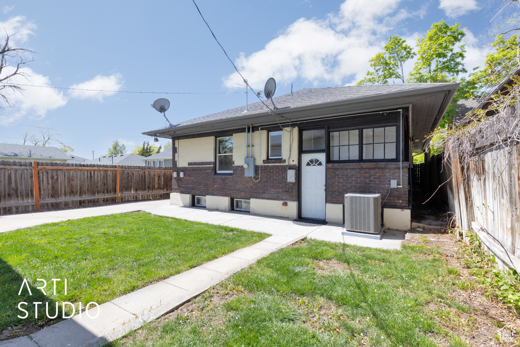 Back of house with a lawn, brick siding, a patio, central air condition unit, and a fenced backyard
