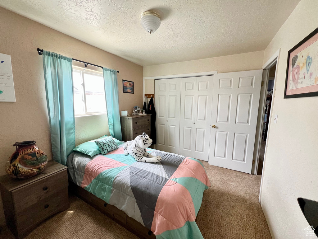 Bedroom featuring carpet flooring, a closet, and a textured ceiling