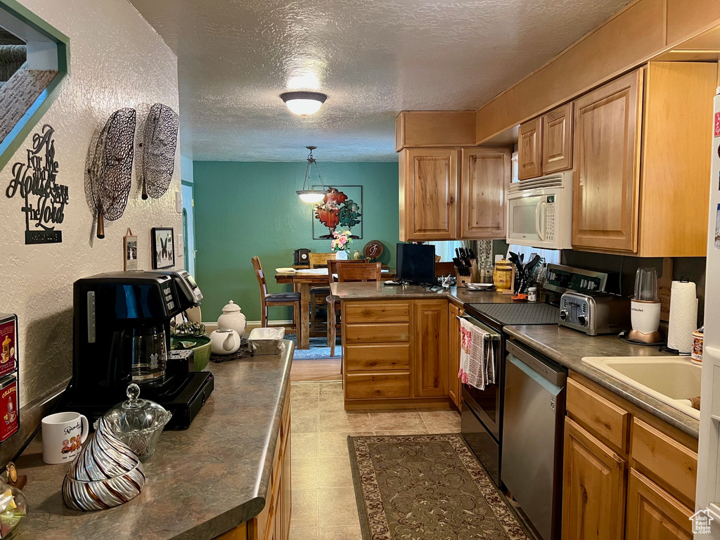 Kitchen featuring range, a textured ceiling, stainless steel dishwasher, and white microwave