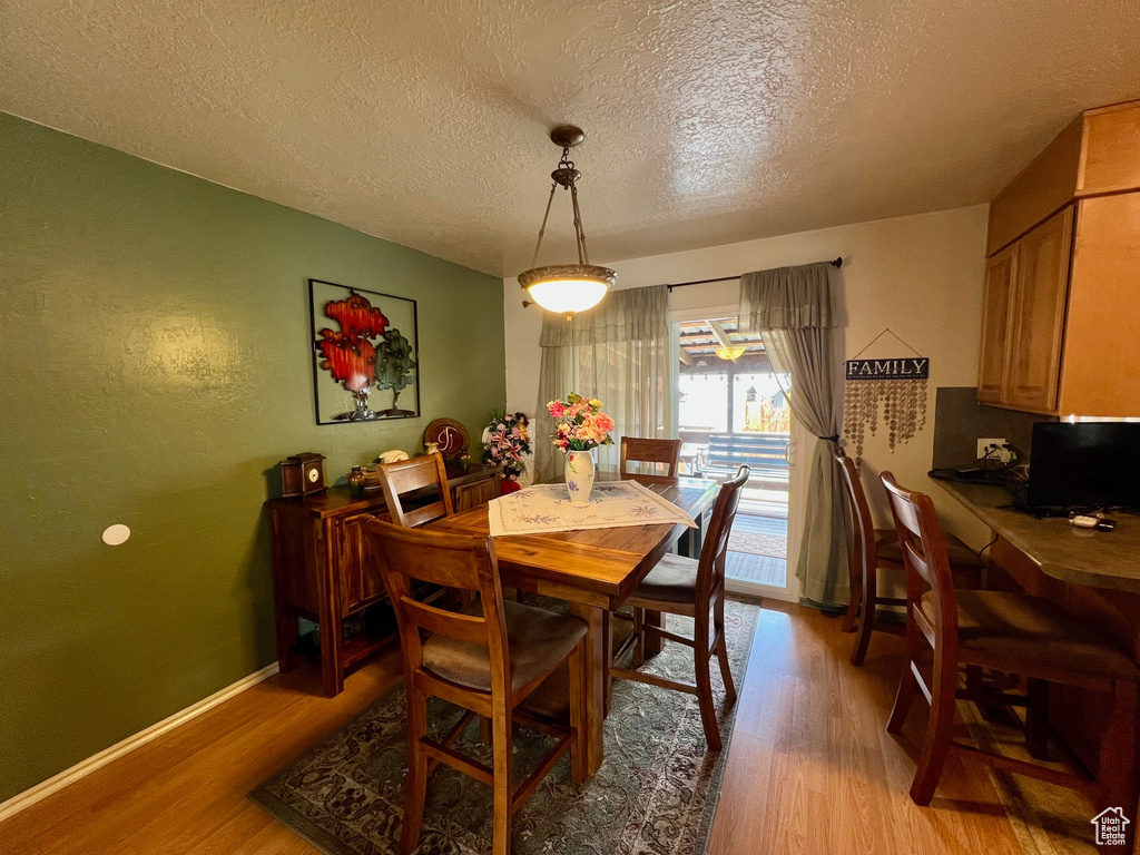 Dining area with a textured ceiling, baseboards, and light wood-type flooring