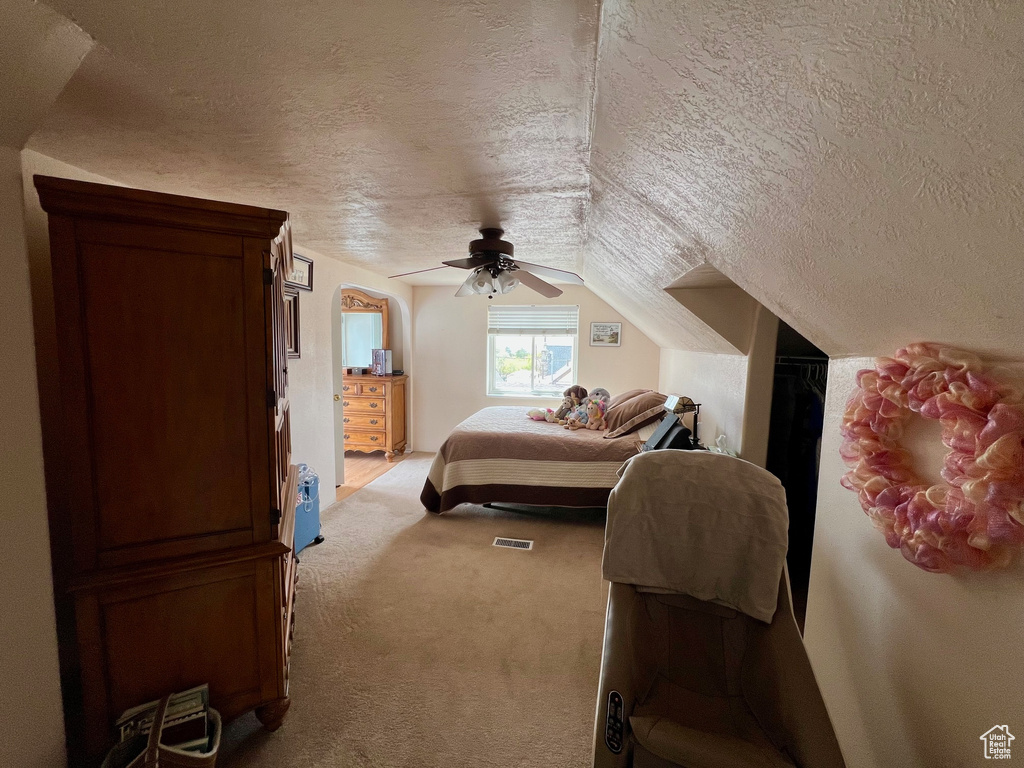 Bedroom with lofted ceiling, carpet floors, a ceiling fan, and a textured ceiling