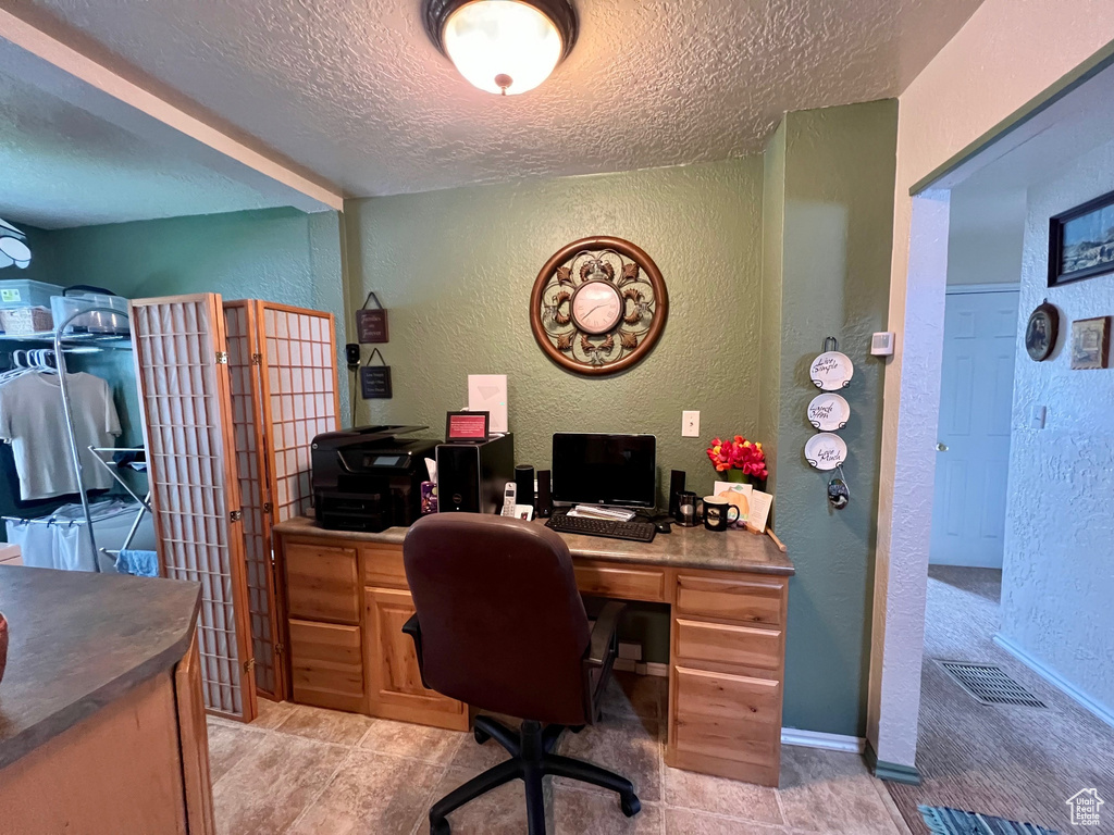 Office featuring baseboards, visible vents, a textured ceiling, and a textured wall