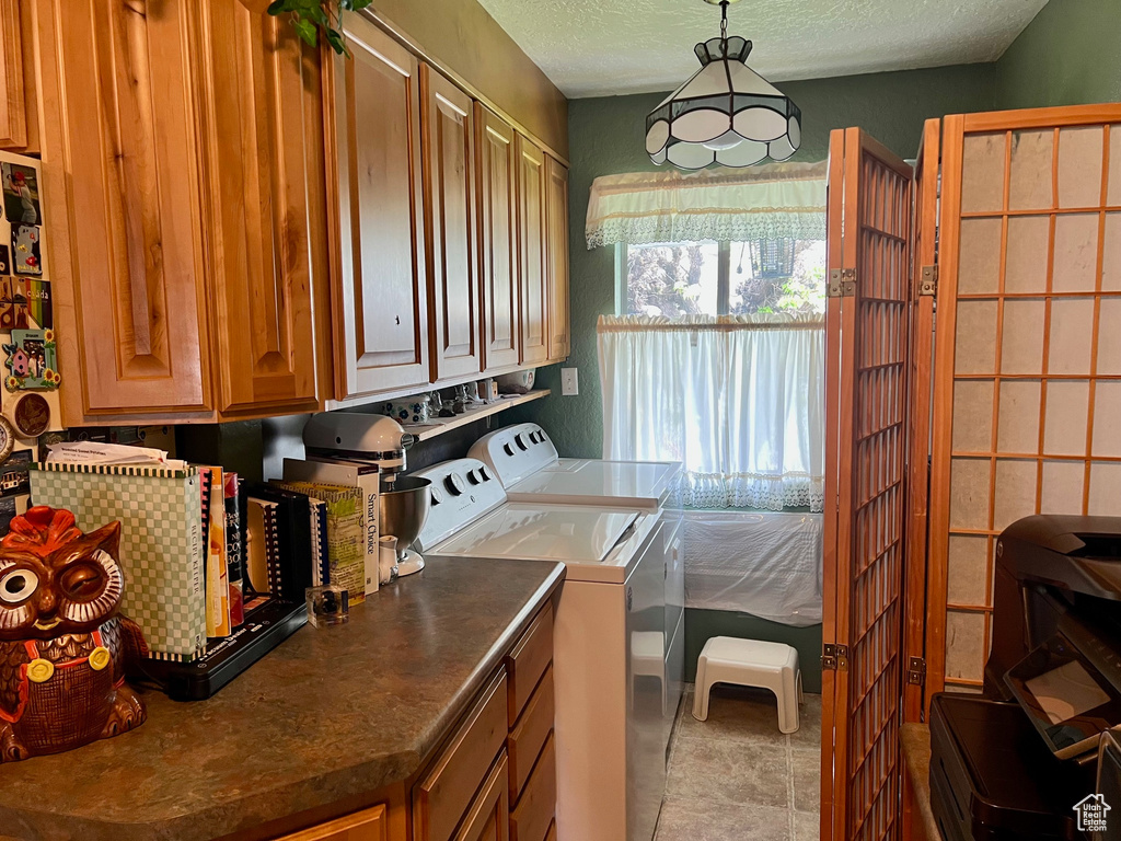 Laundry area with a textured ceiling, independent washer and dryer, and cabinet space