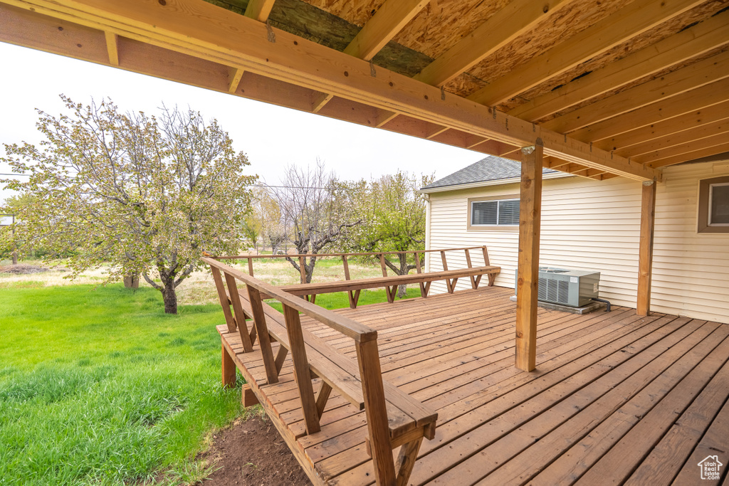 Deck featuring a yard and central air condition unit