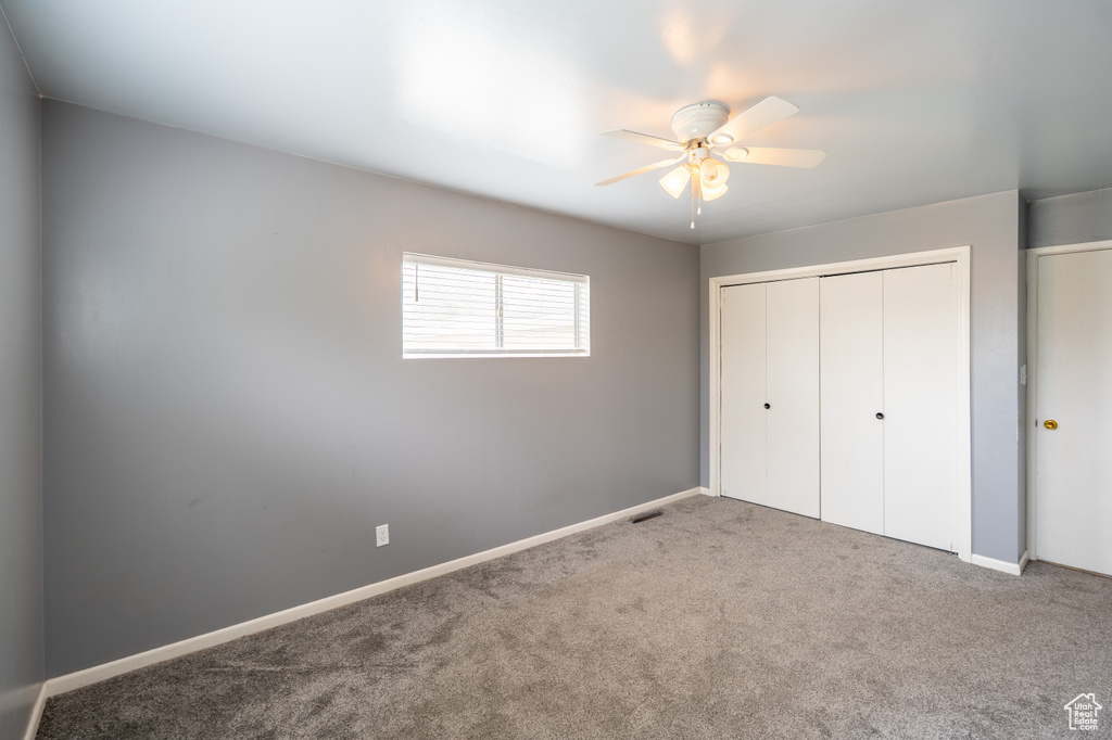 Unfurnished bedroom featuring carpet, a closet, baseboards, and a ceiling fan