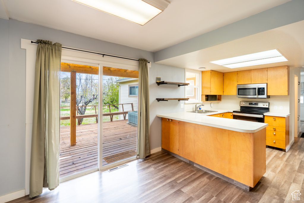 Kitchen with light wood-style flooring, a sink, open shelves, stainless steel appliances, and visible vents