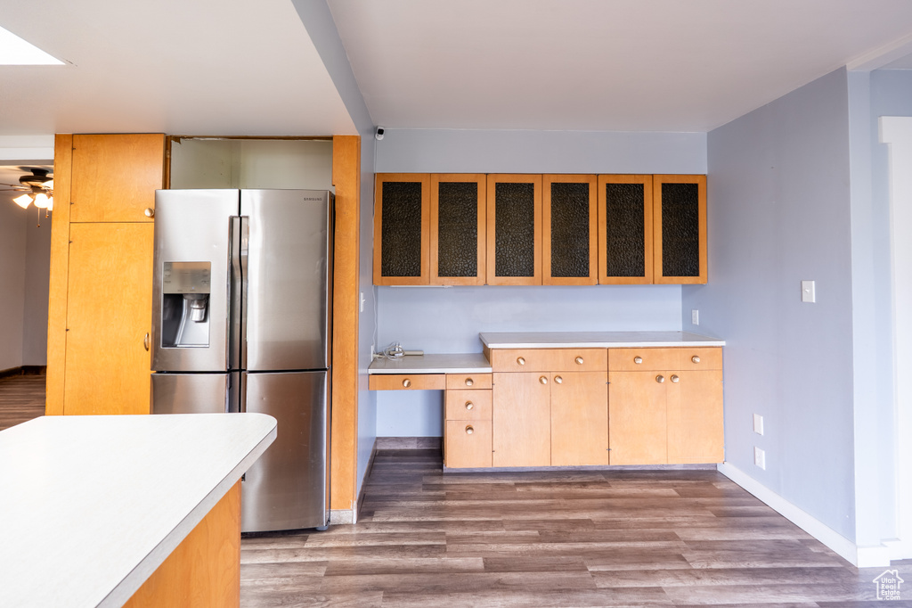 Kitchen featuring stainless steel fridge with ice dispenser, light countertops, baseboards, and wood finished floors