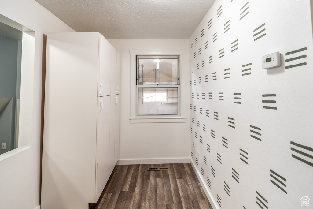 Hall featuring baseboards, dark wood finished floors, visible vents, and a textured ceiling
