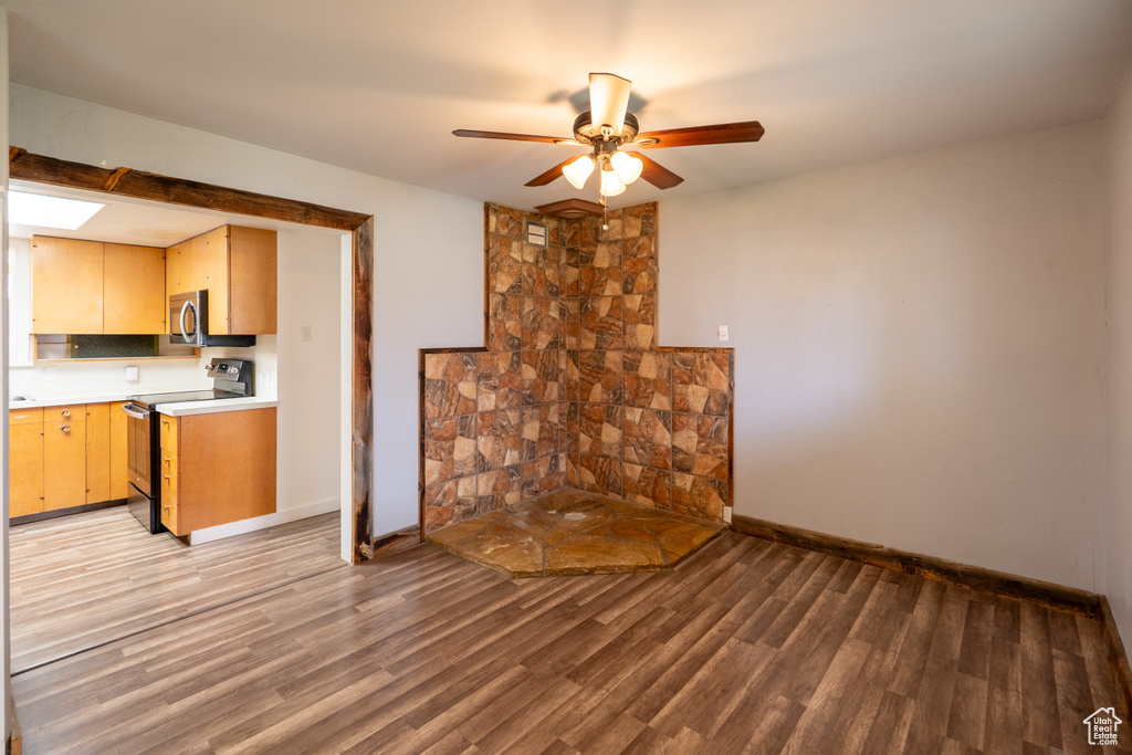 Unfurnished living room featuring light wood-type flooring, baseboards, and ceiling fan