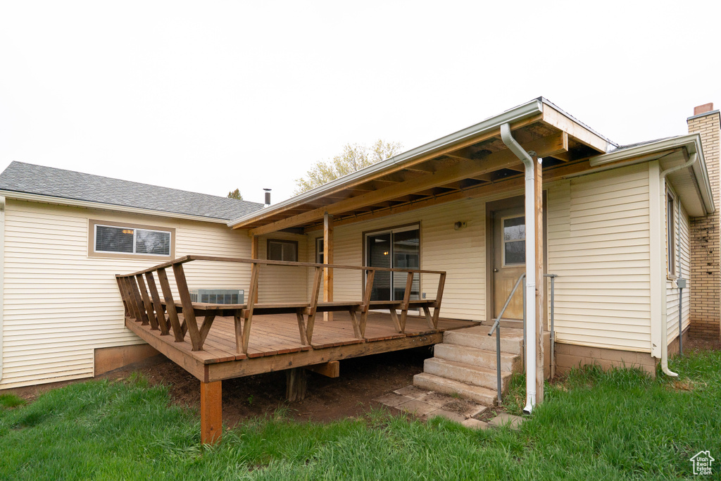 Back of house featuring cooling unit, a shingled roof, and a deck
