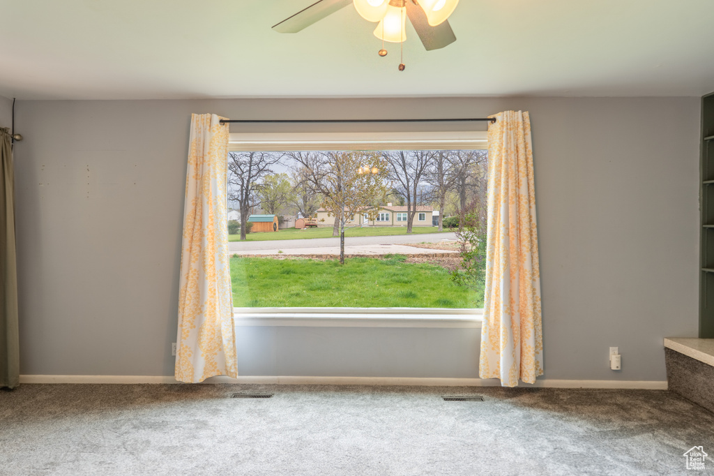 Empty room with ceiling fan, carpet, baseboards, and visible vents