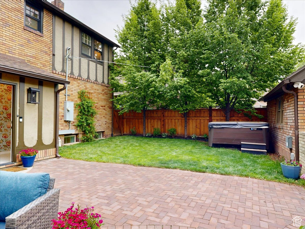 Exterior space with a patio area, a hot tub, and a fenced backyard