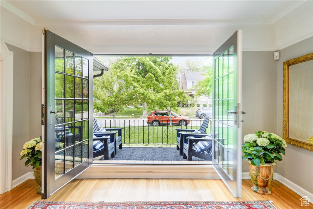 Doorway featuring crown molding, wood finished floors, and baseboards