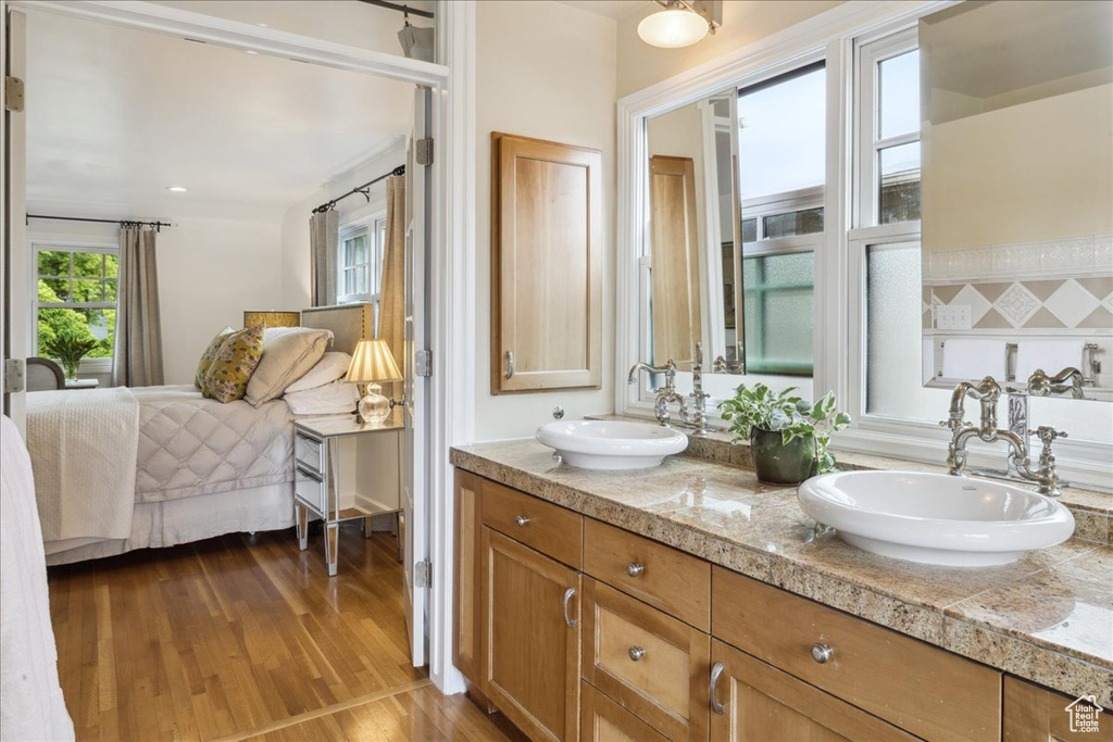 Bathroom featuring double vanity, ensuite bathroom, wood finished floors, and a sink