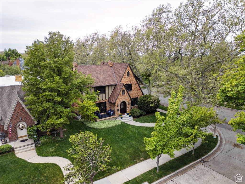 Tudor house featuring stone siding, brick siding, and a front lawn