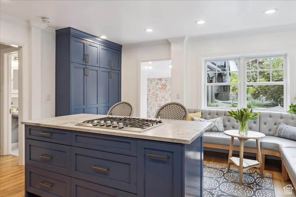 Kitchen with blue cabinetry, light wood finished floors, crown molding, and stainless steel gas cooktop