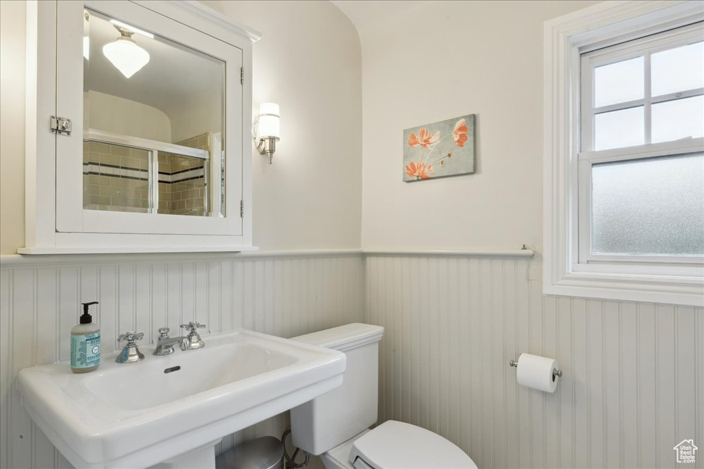 Full bath featuring a wainscoted wall, toilet, a shower stall, and a sink