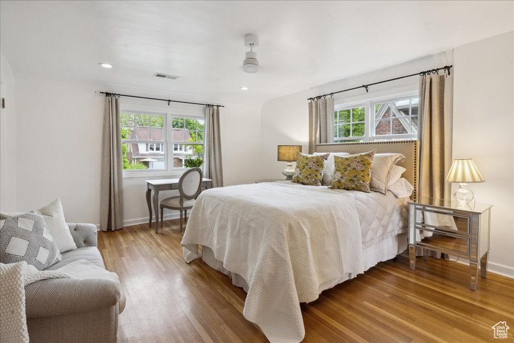 Bedroom with baseboards, arched walkways, visible vents, and wood finished floors