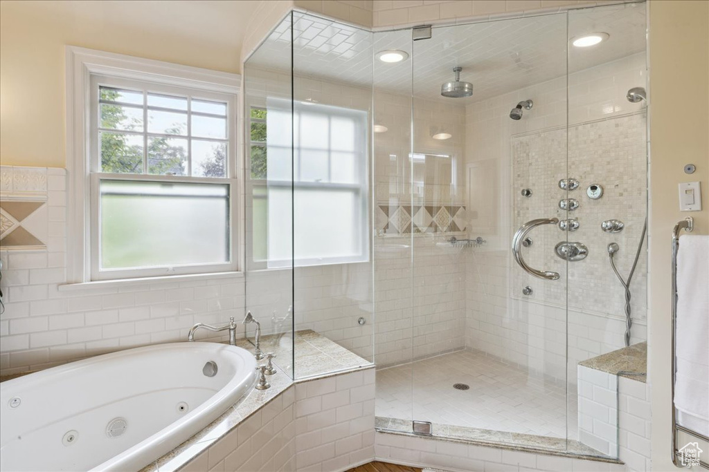 Bathroom with a stall shower, a jetted tub, and a wealth of natural light