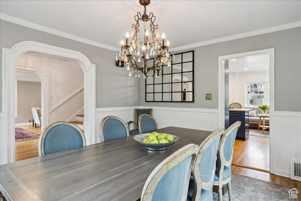 Dining room featuring stairway, crown molding, arched walkways, and wood finished floors