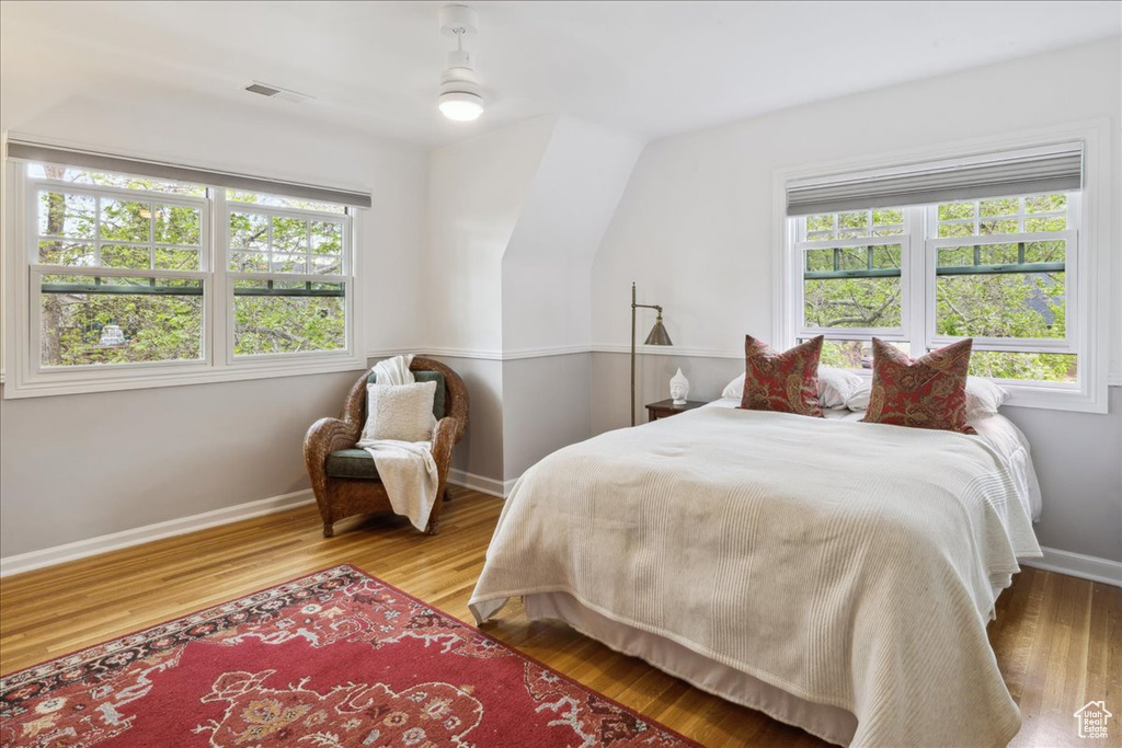 Bedroom with multiple windows, visible vents, wood finished floors, and baseboards