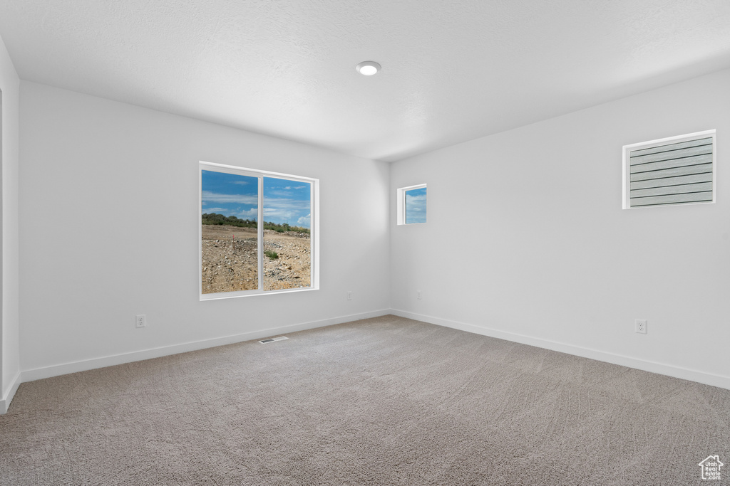 Carpeted empty room with visible vents and baseboards