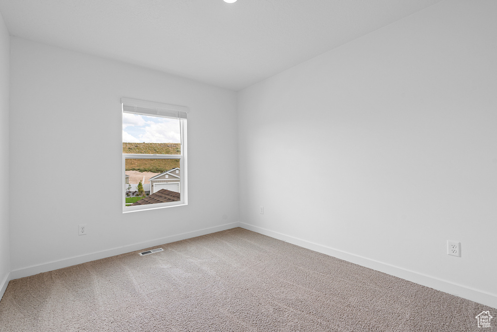 Carpeted spare room with visible vents and baseboards