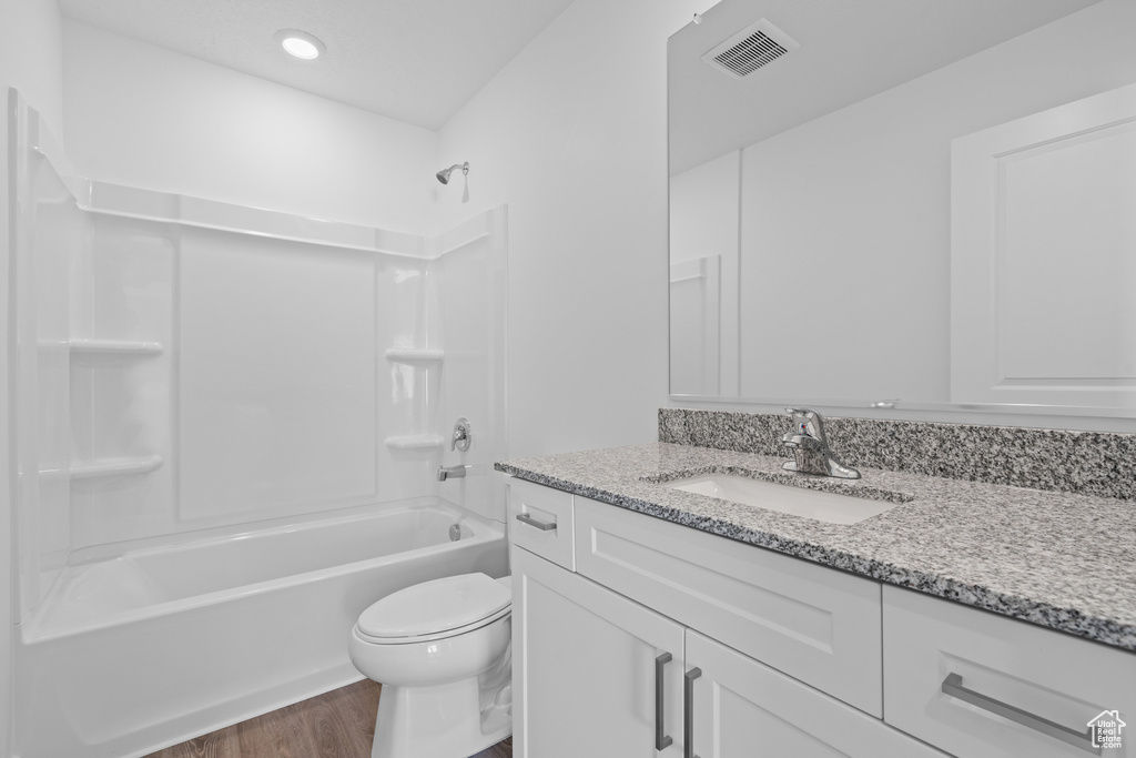 Bathroom with shower / bathing tub combination, toilet, wood finished floors, vanity, and visible vents
