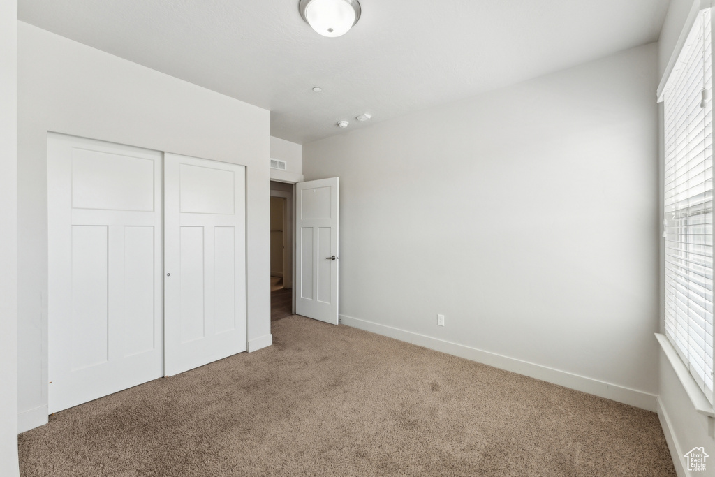 Unfurnished bedroom with carpet flooring, a closet, and baseboards