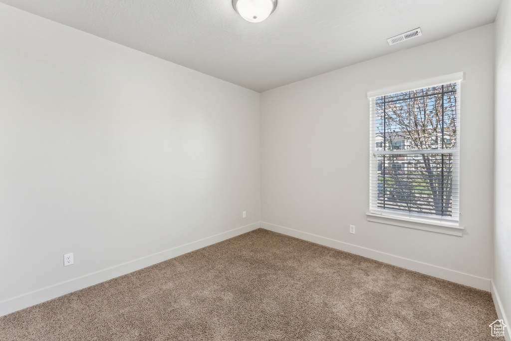Unfurnished room with carpet flooring, baseboards, and visible vents