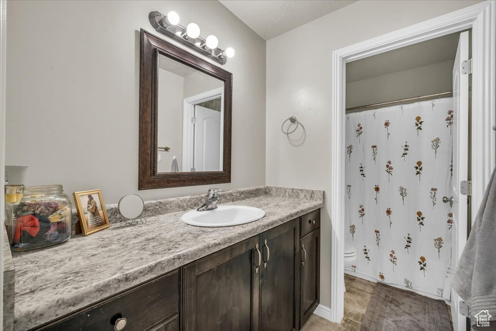 Bathroom featuring a shower with curtain, vanity, and toilet