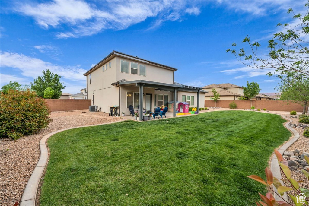 Rear view of house featuring a yard, cooling unit, a patio, stucco siding, and a fenced backyard