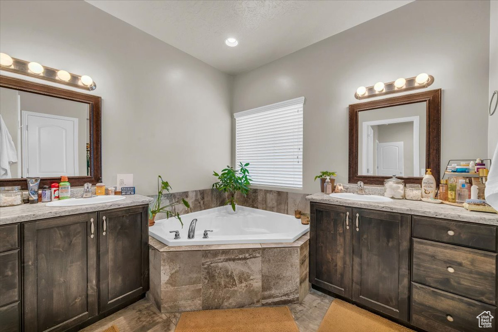 Bathroom featuring a sink, two vanities, and a bath