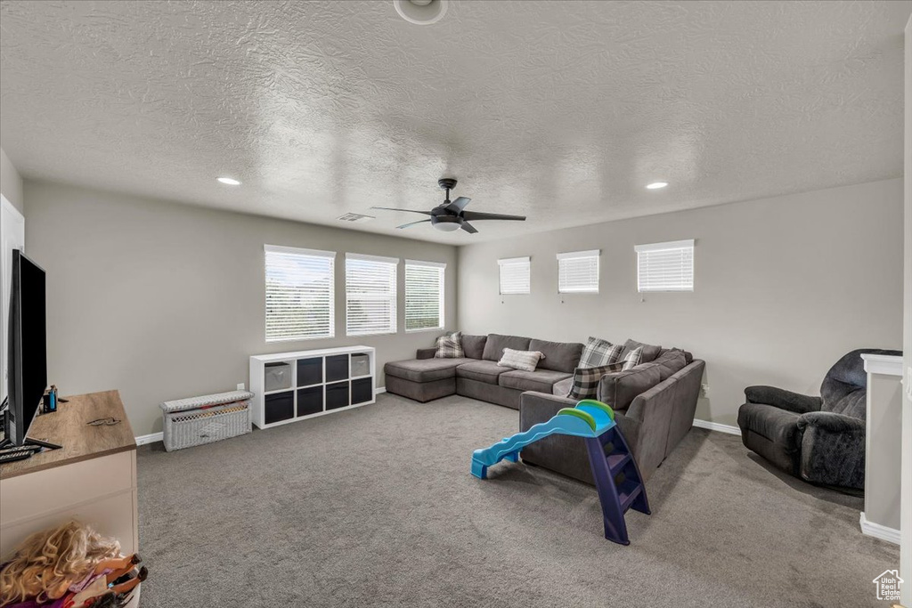Carpeted living area with a textured ceiling, ceiling fan, and recessed lighting