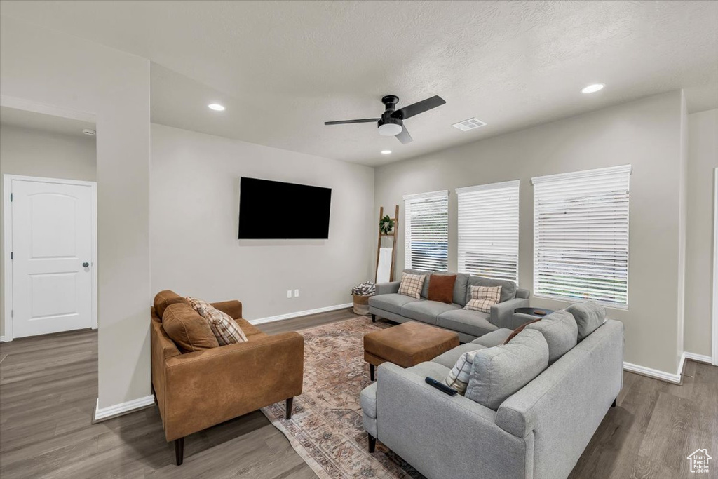 Living area with baseboards, ceiling fan, visible vents, and wood finished floors