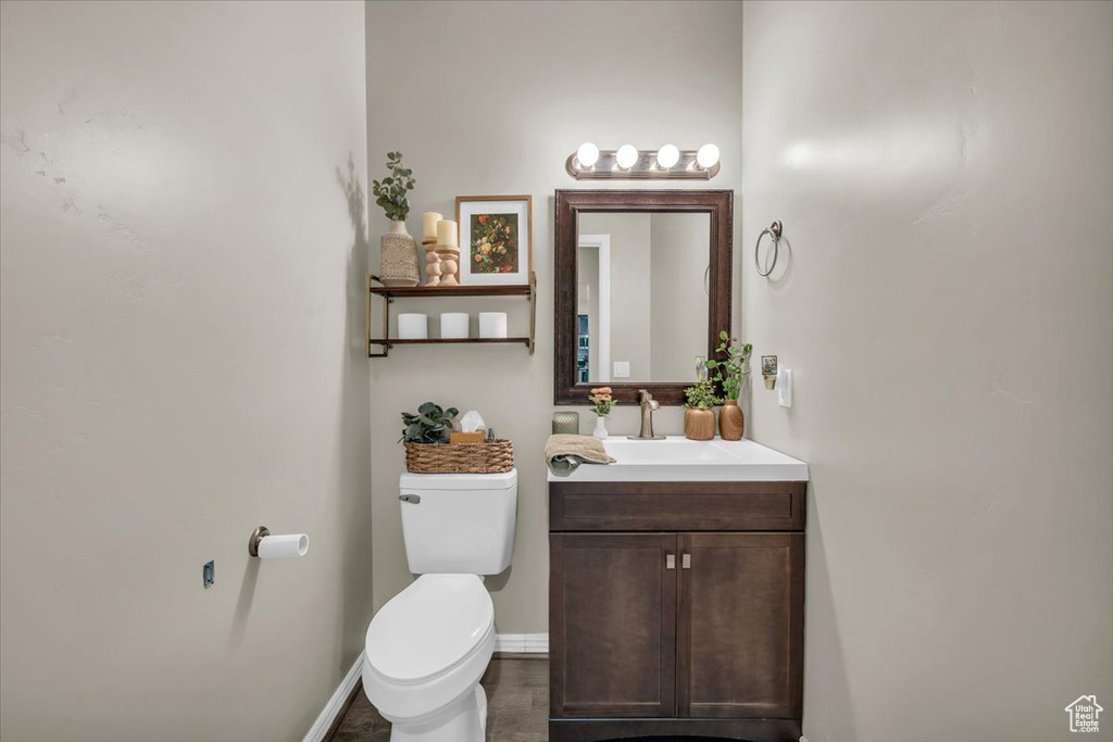 Half bathroom with toilet, baseboards, and vanity