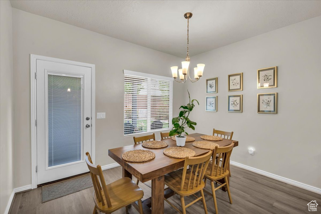 Dining area with wood finished floors, baseboards, and a notable chandelier