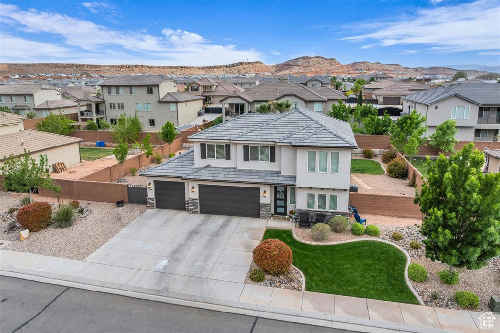 View of front of property with a residential view, a tiled roof, stucco siding, concrete driveway, and fence private yard